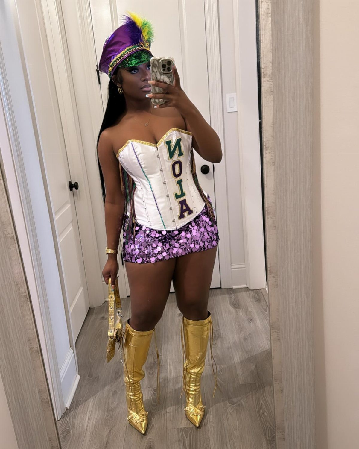 Woman in purple and gold Mardi Gras outfit with corset and metallic boots.
