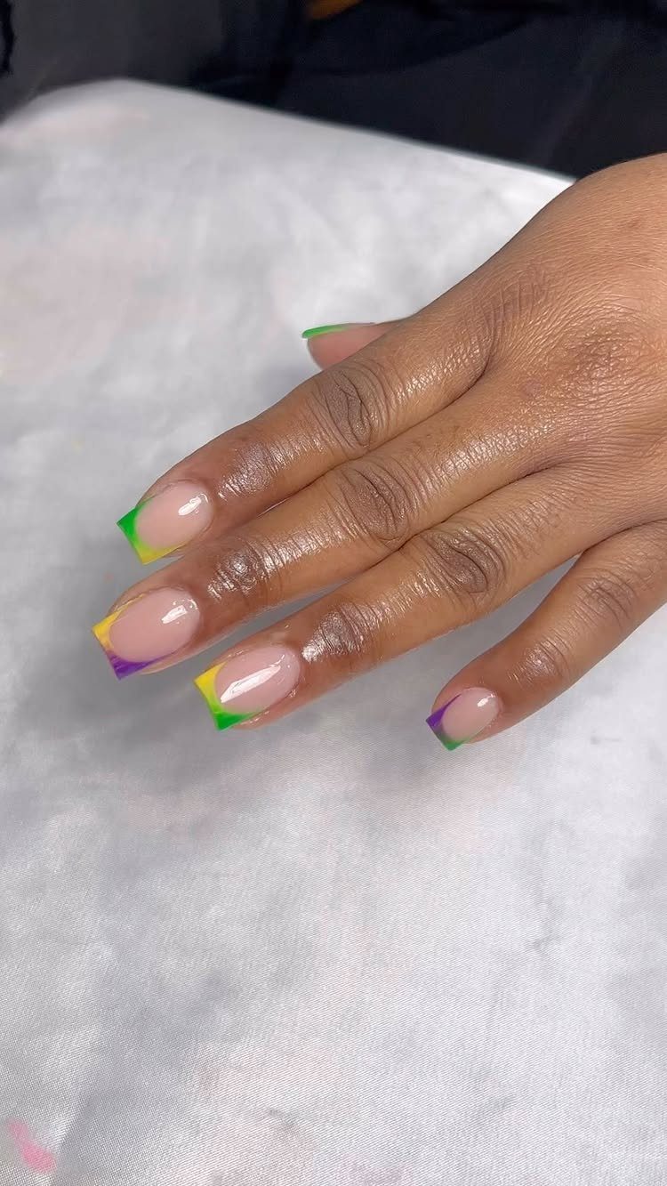 Hand with almond nails featuring purple, green, and gold French manicure tips.