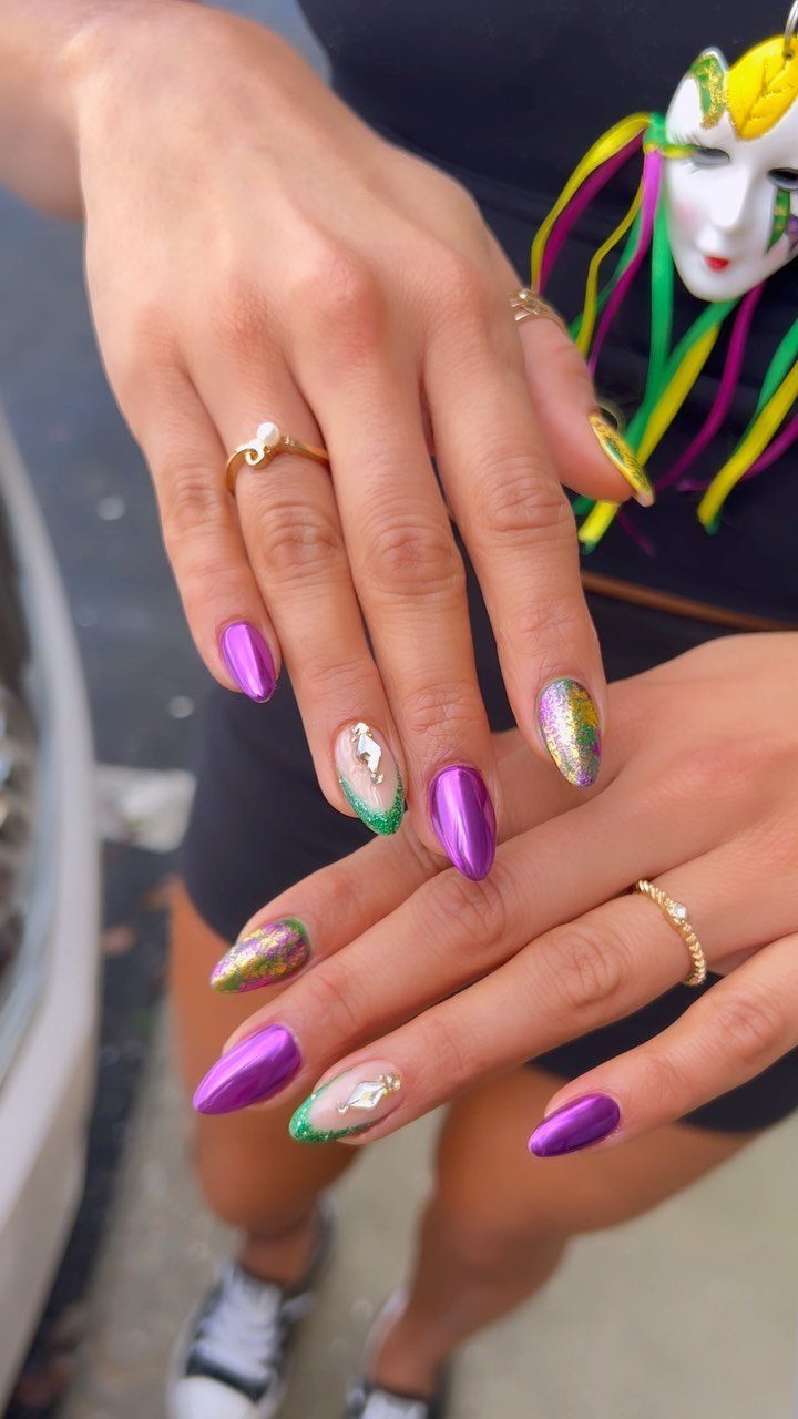 Hands with purple, green, and gold glitter nails and a Mardi Gras mask.