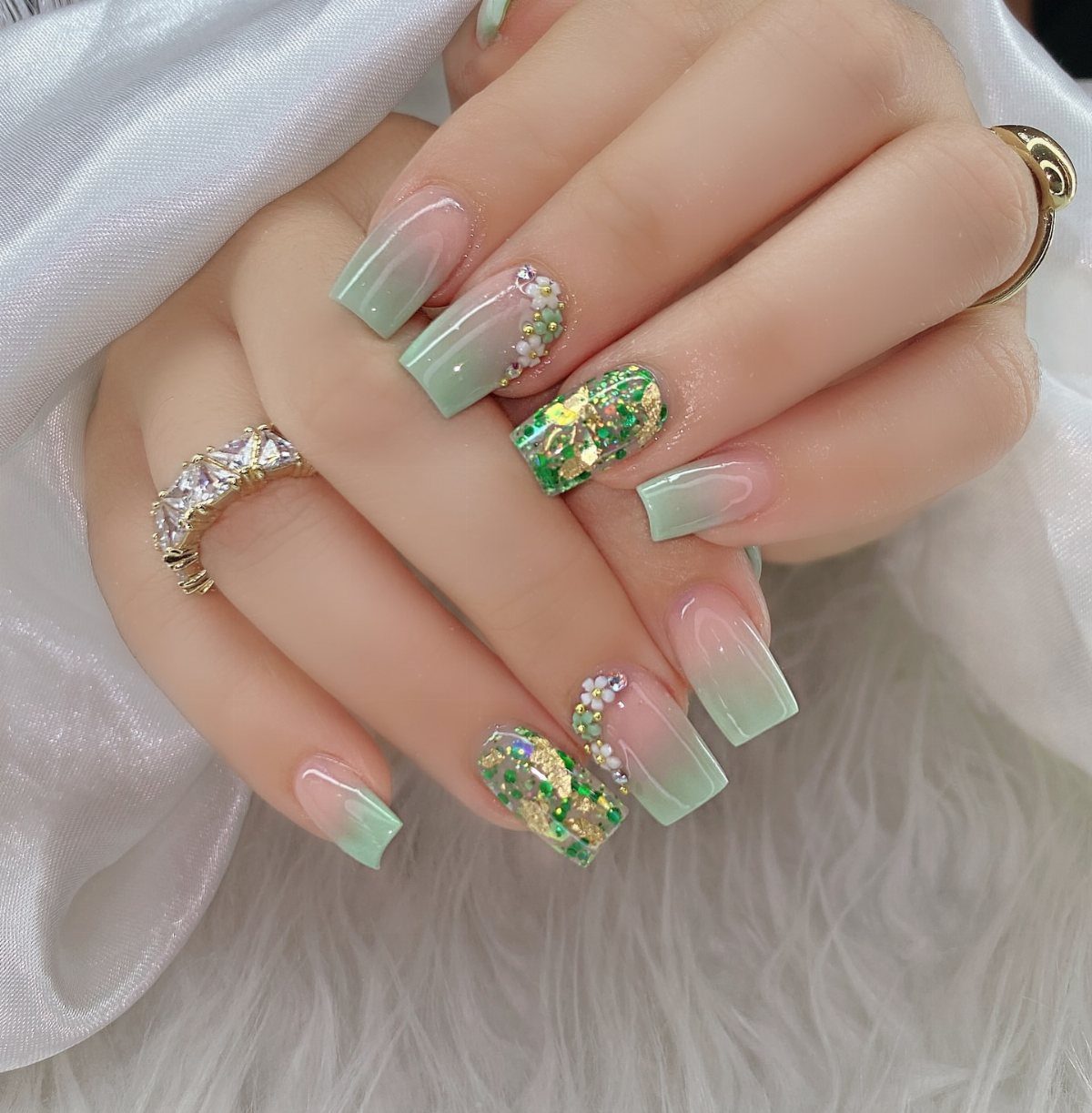 Long coffin nails with light green ombre and sparkling green glitter accents.