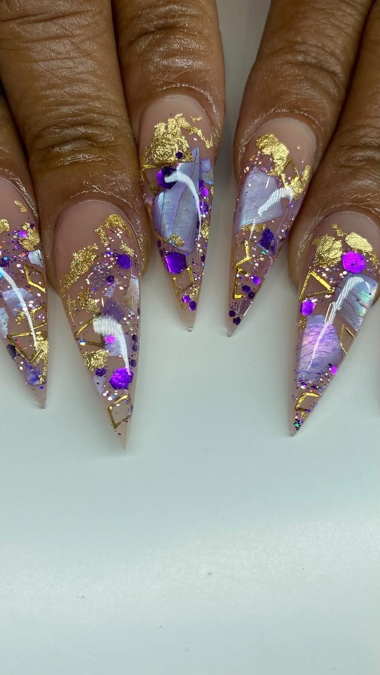 Stiletto nails decorated with purple glitter and gold foil for Mardi Gras.