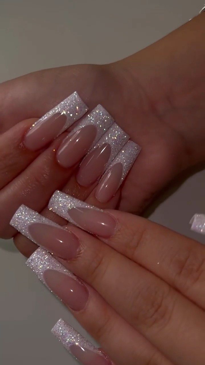 Long coffin-shaped nails with nude bases and shimmering silver glitter French tips.
