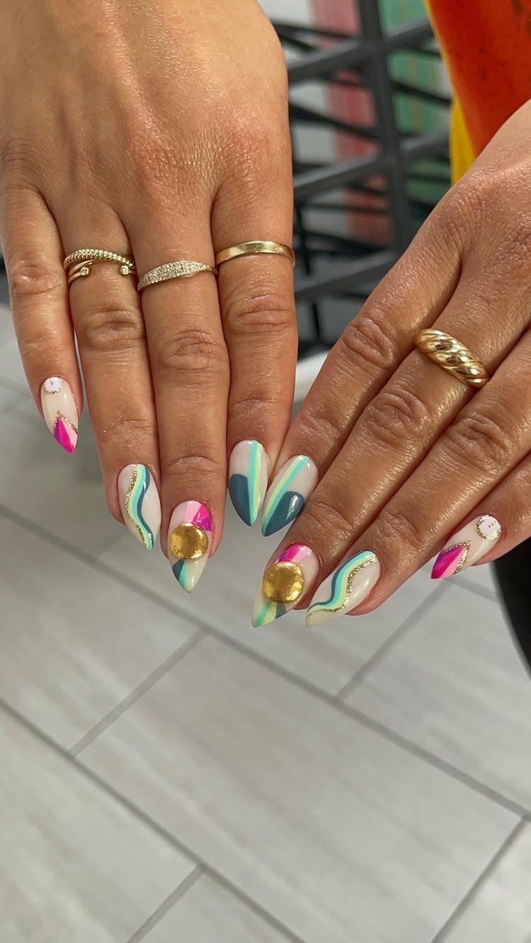 Colorful abstract nail art with gold lines and glitter circles on almond nails.