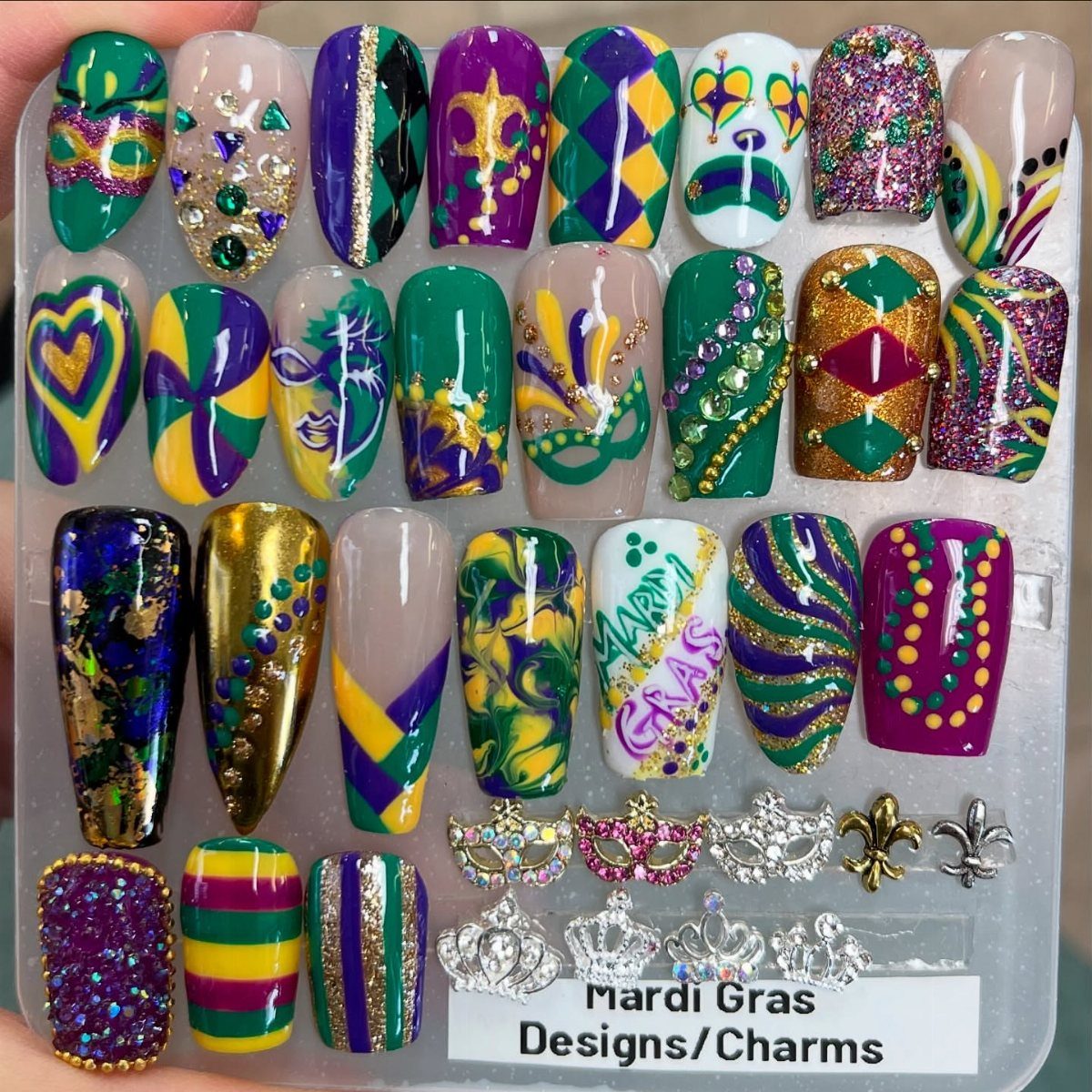 Mardi Gras themed press-on nails in purple, green, and gold with decorative charms.