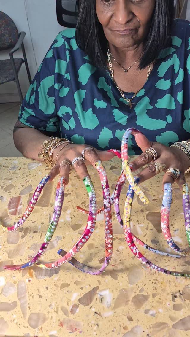 Extremely long curved acrylic nails with purple, green, and gold colorful patterns.