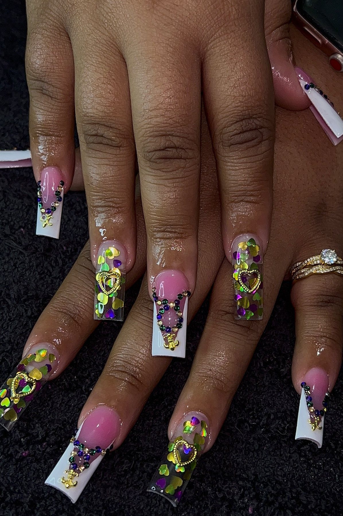 Long square nails featuring white French tips, purple glitter, and gold charms.