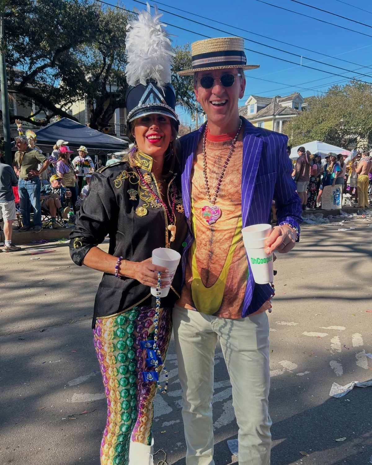 Man in purple blazer and woman in sequined pants posing at Mardi Gras.