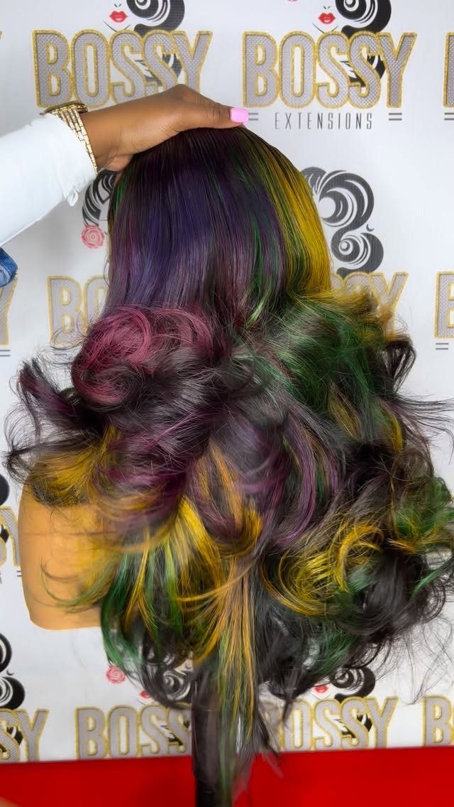 Voluminous curly wig with purple, green, and gold streaks on a person.
