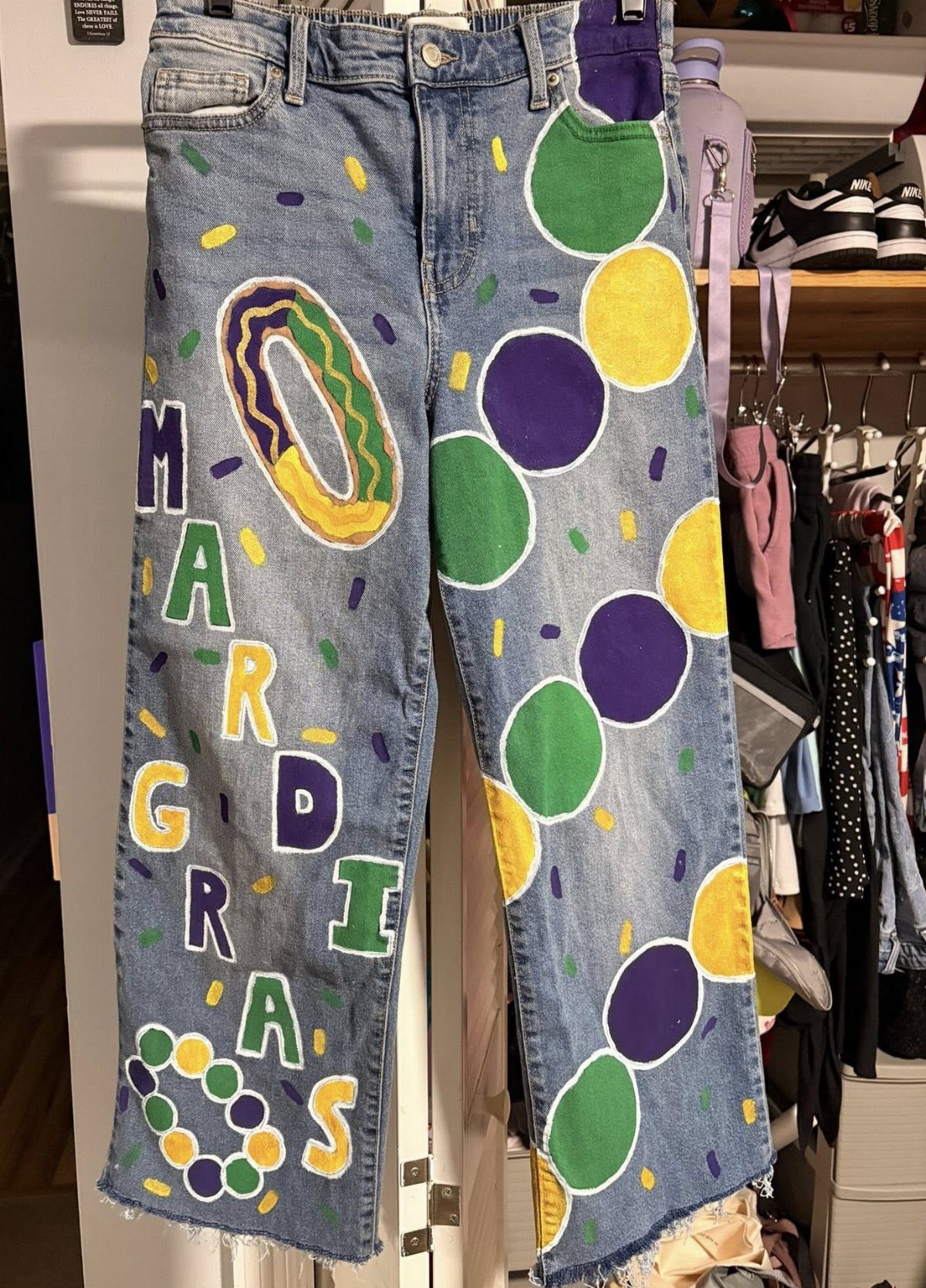 Blue denim jeans painted with Mardi Gras colors and themed bead patterns.