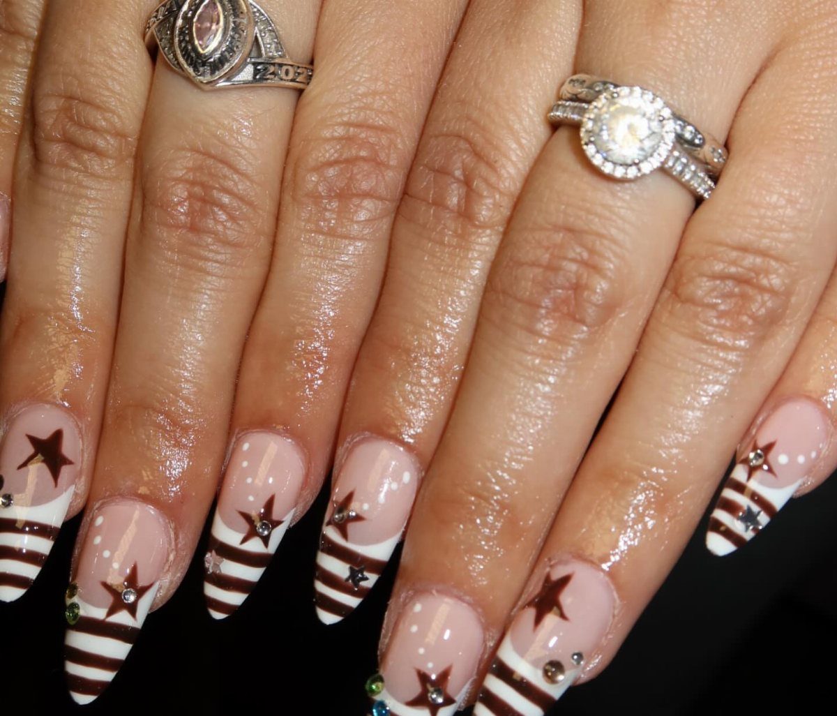 Patriotic almond-shaped nails with red and white stripes and red stars.