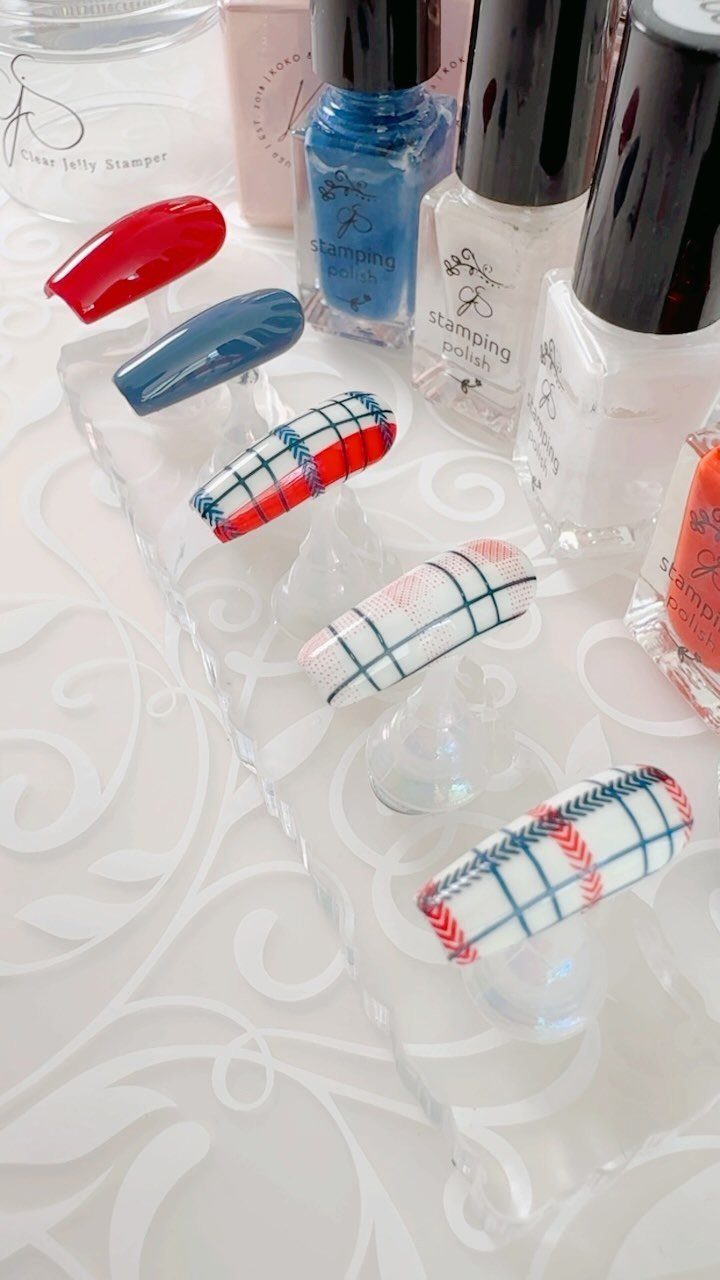 Artificial nail tips with red, white, and blue plaid patterns and solid colors.