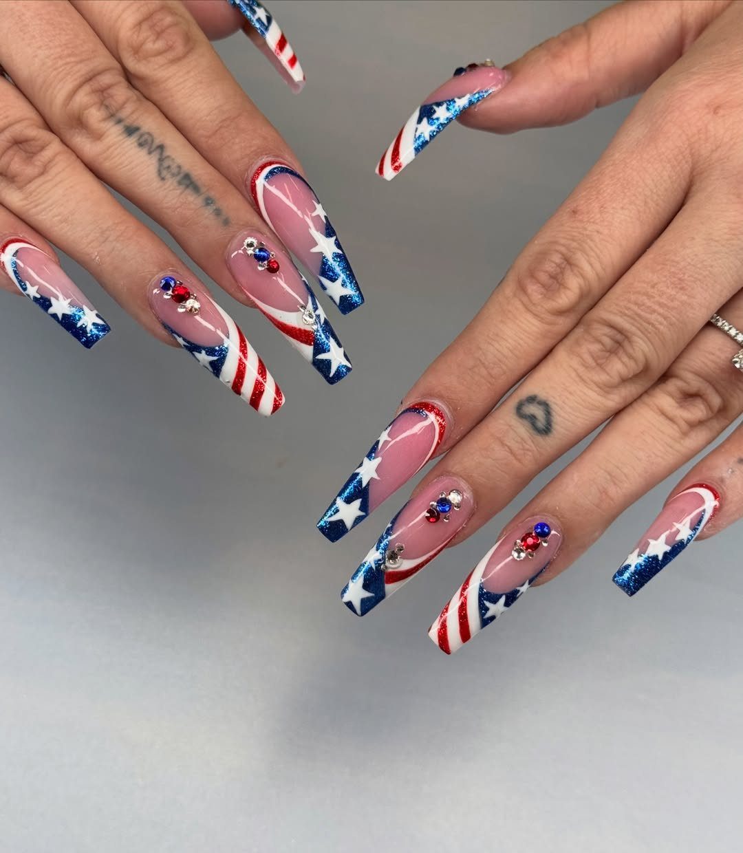 Patriotic coffin nails with red and white stripes and blue stars with rhinestones.