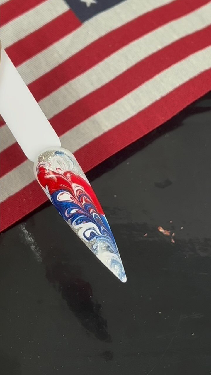 Marbled red, white, and blue nail art against an American flag background.