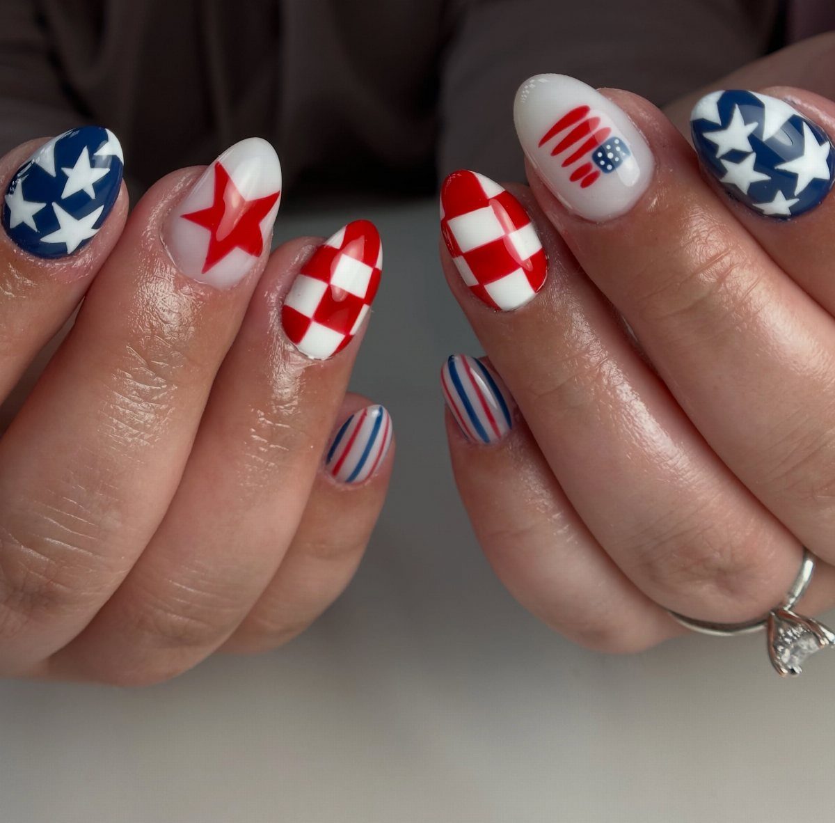 Patriotic red, white, and blue nail art with stars and stripes on almond nails.