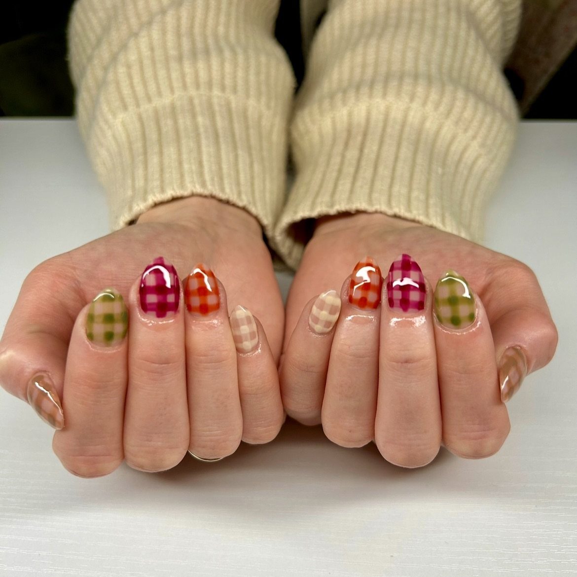 Short nails with colorful gingham checkered patterns in pink, orange, green, and beige.