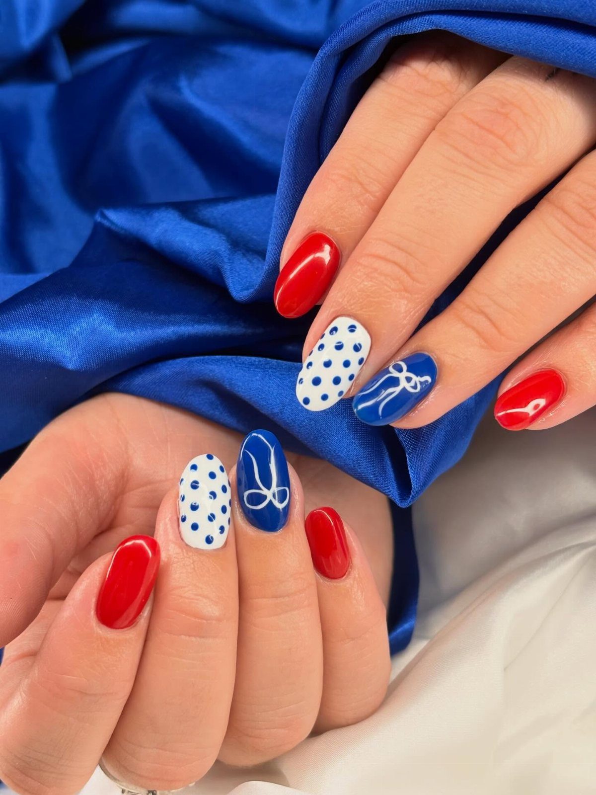 Short oval nails with red, blue, and white polka dot patriotic designs.