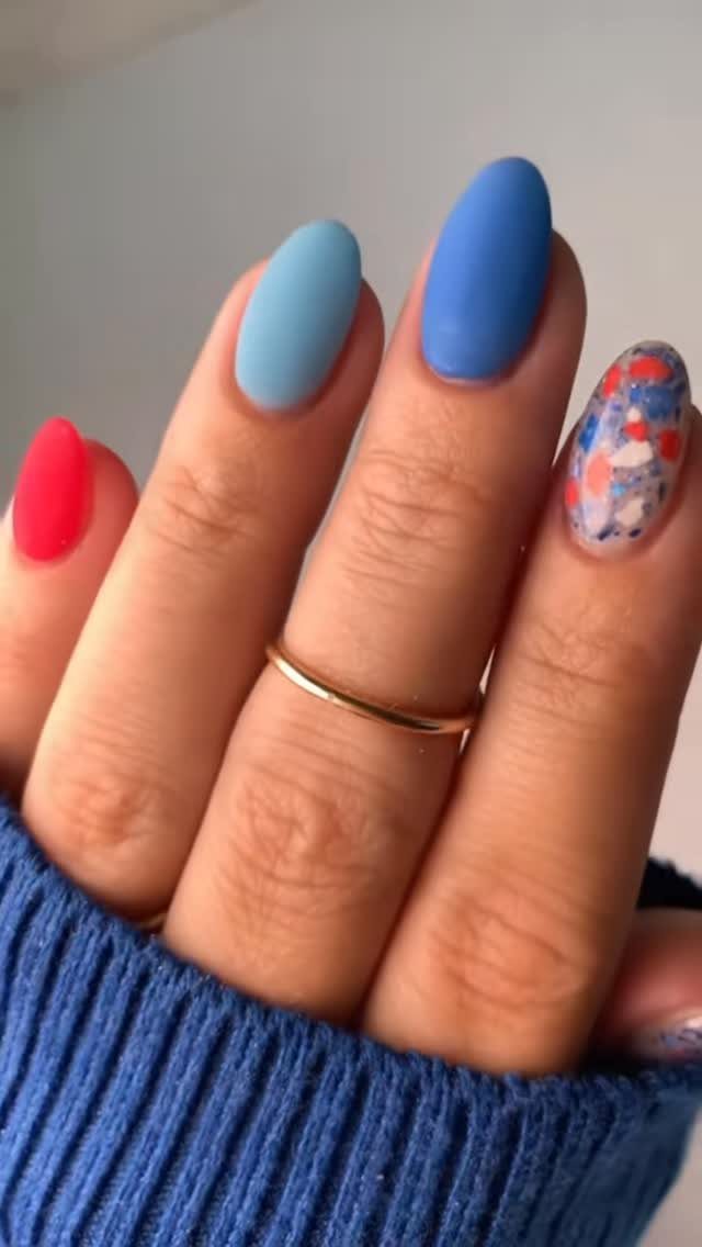 Hand with red, white, and blue manicured nails wearing a blue sweater