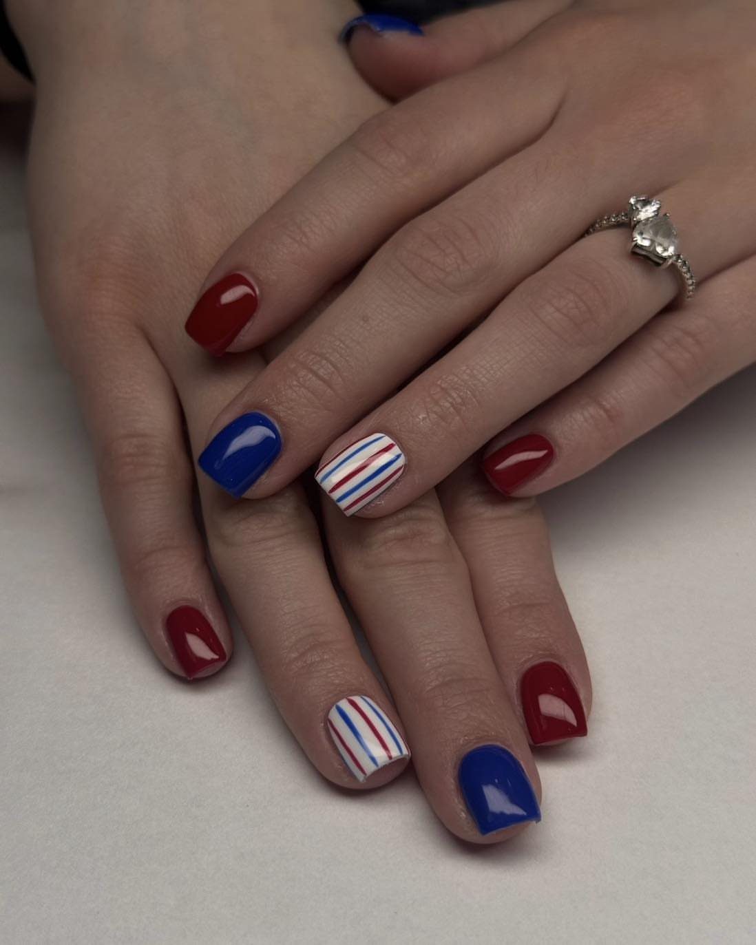 Short nails painted red, blue, and striped white, red, and blue on hands.