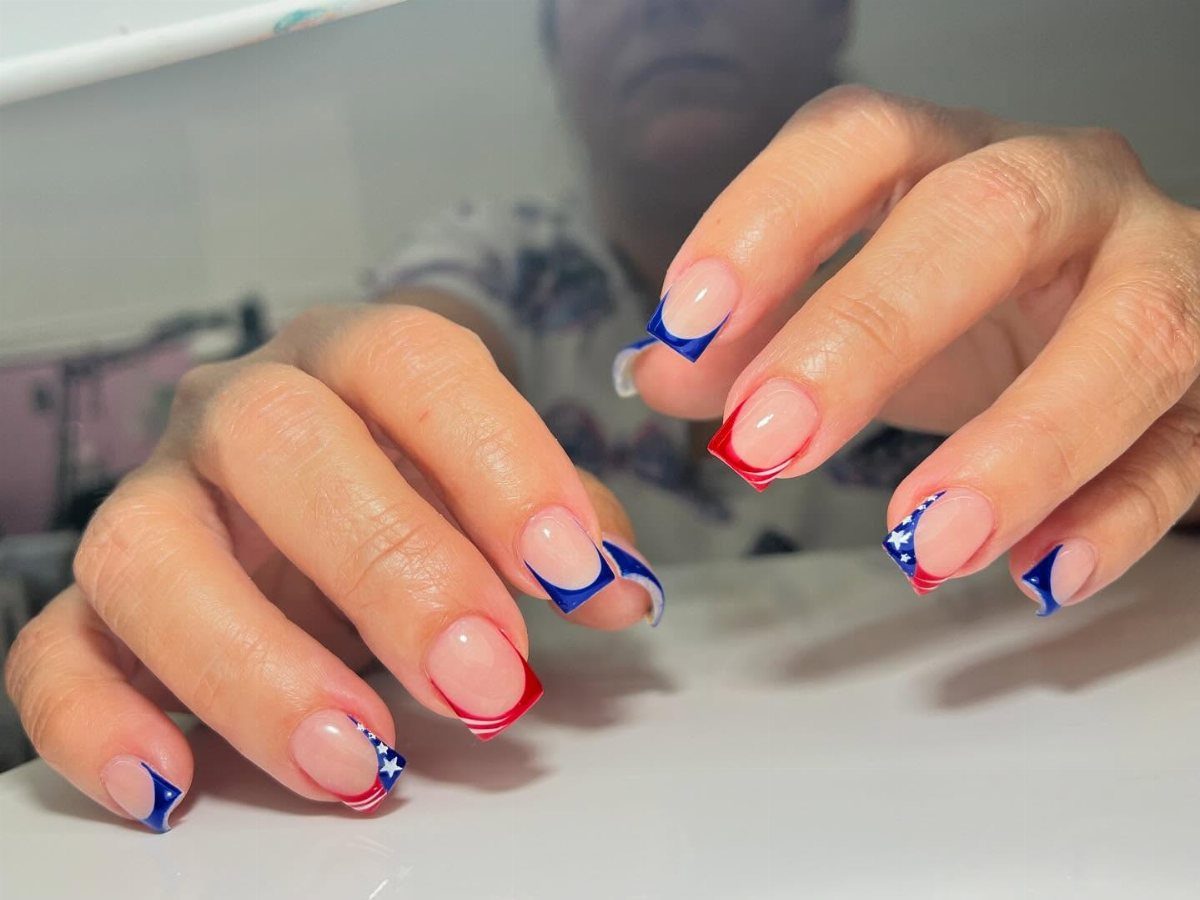 Hands with red, white, and blue patriotic nail art featuring stars and stripes.