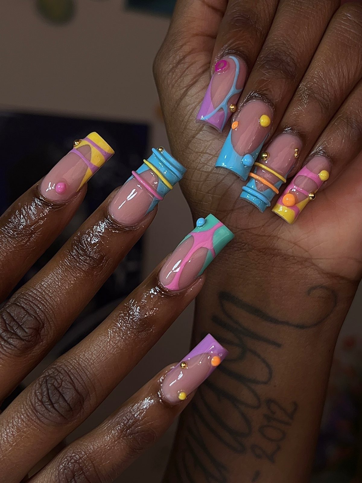 Colorful coffin nails with 3D raised dots and swirls in pink, blue, and yellow.