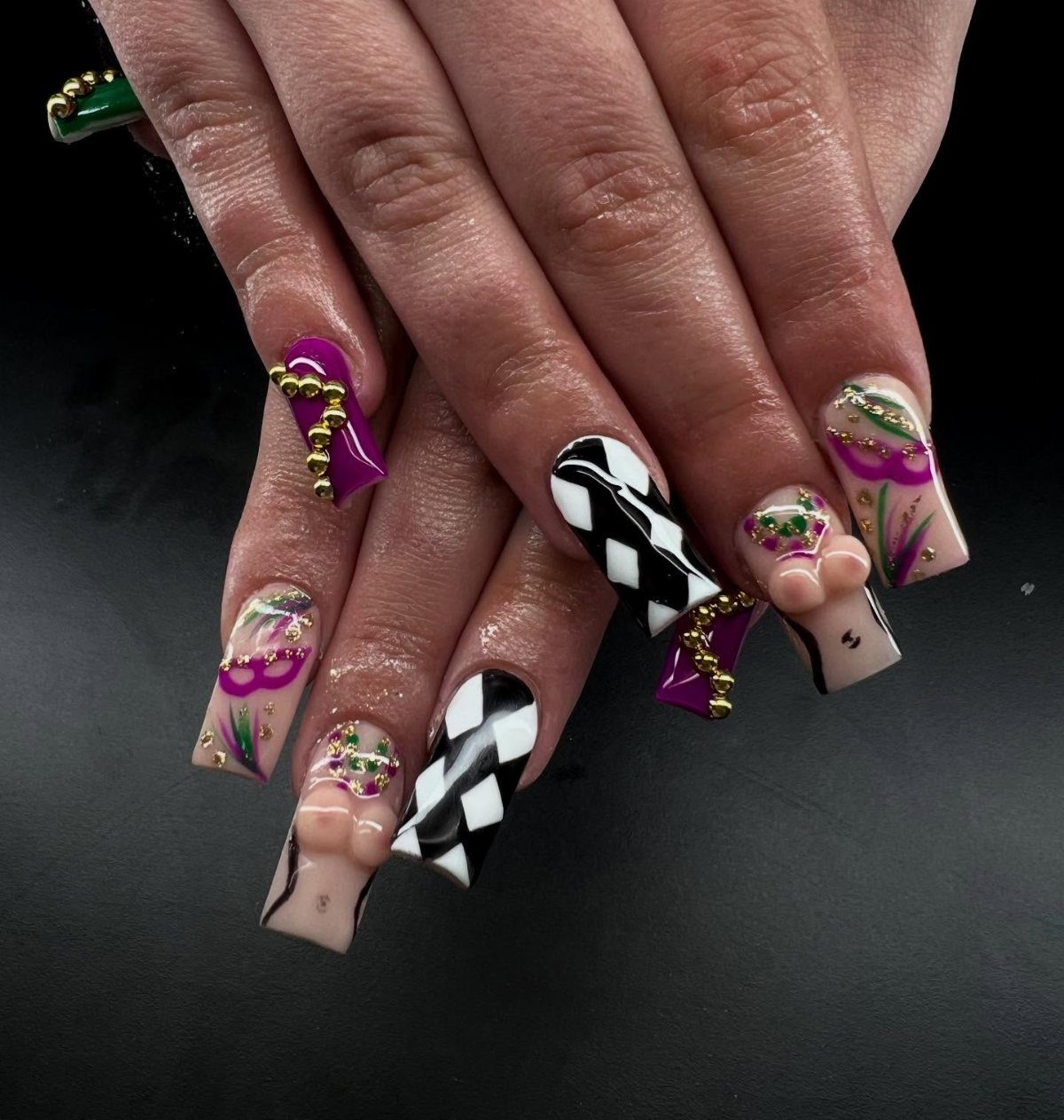 Long coffin nails with purple, green, and gold colors and gold bead accents.