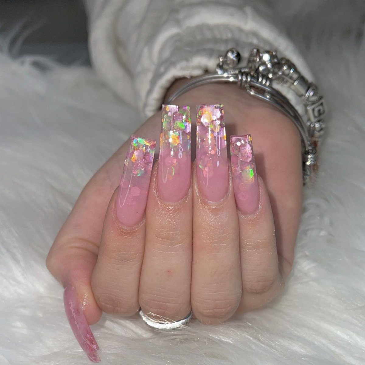 Pink square nails with colorful iridescent glitter ombré tips on a white background