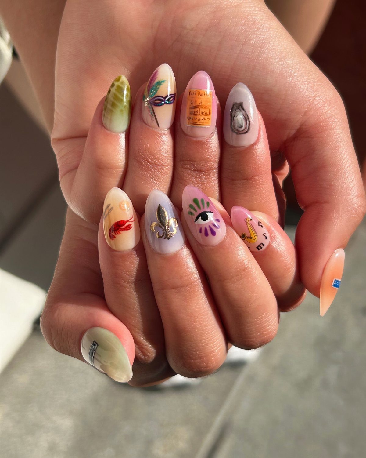 Almond-shaped nails featuring New Orleans themed art like a fleur-de-lis and crawfish.