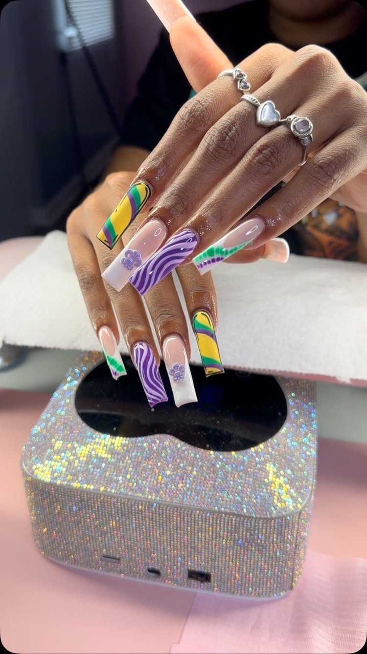 Long coffin nails with purple, green, and gold Mardi Gras themed nail art.