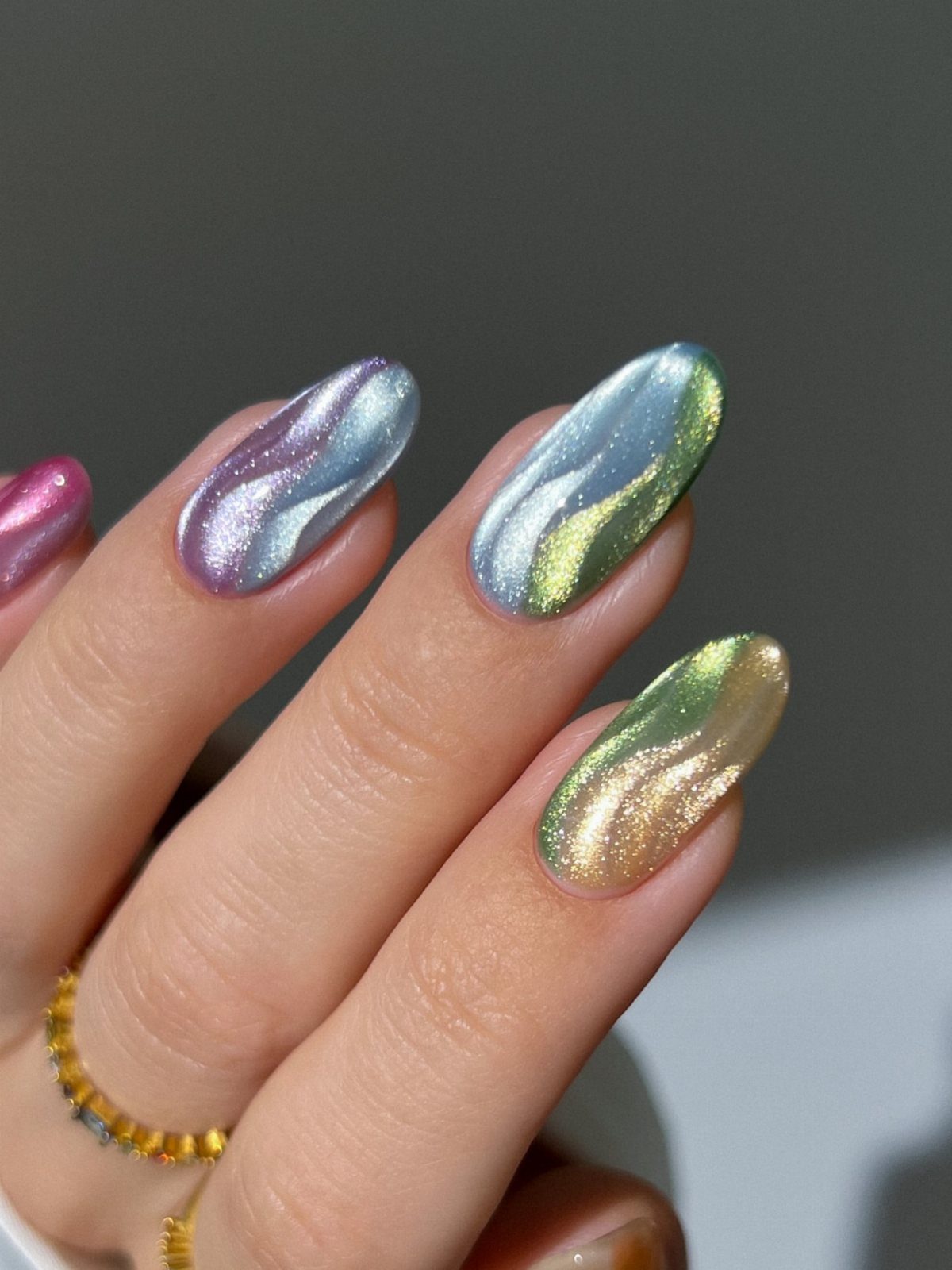 Iridescent aurora nails with swirling purple, blue, and gold metallic shimmer finishes.