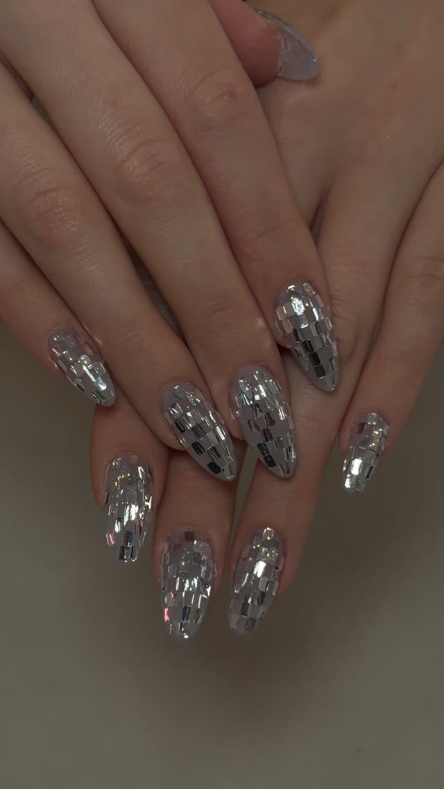 Almond-shaped nails with a silver mirrored mosaic disco ball design on a hand.