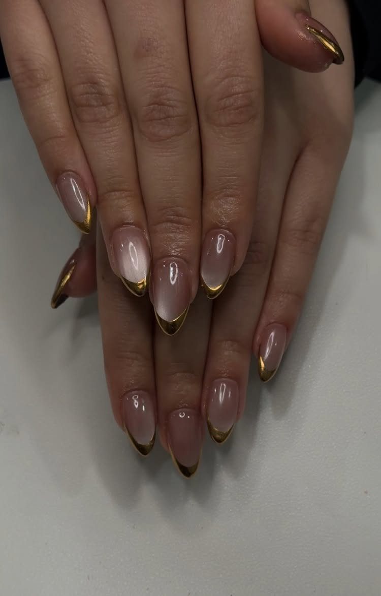 Almond-shaped nails with nude gradient bases and metallic gold chrome French tips.