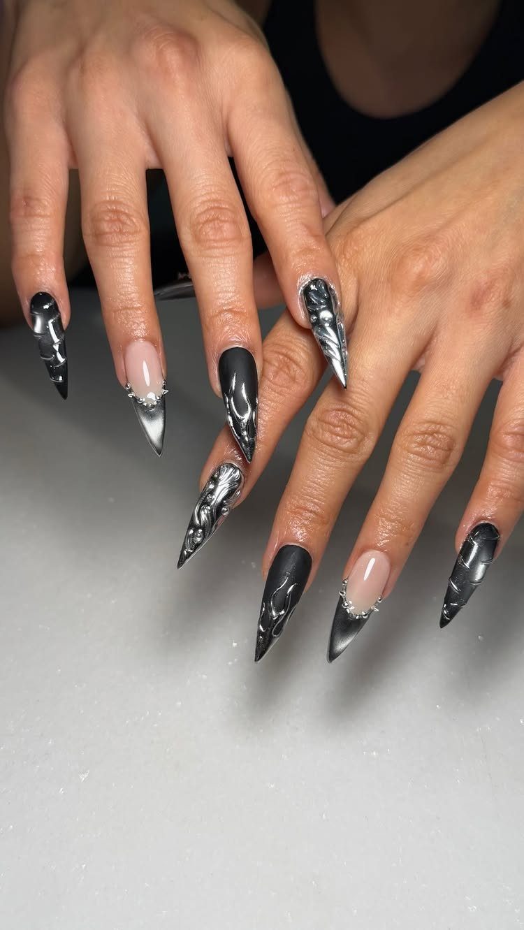 Stiletto nails with midnight black chrome and silver metallic swirl designs.