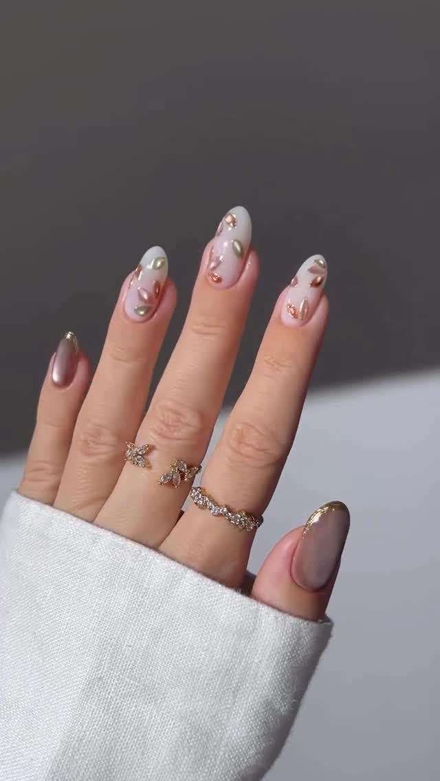 Almond-shaped nails with nude base and rose gold metallic floral accents and gradients.