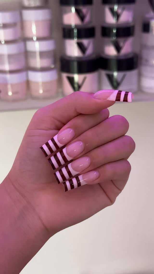 Almond-shaped nails with nude base and dark horizontal stripes on the tips.