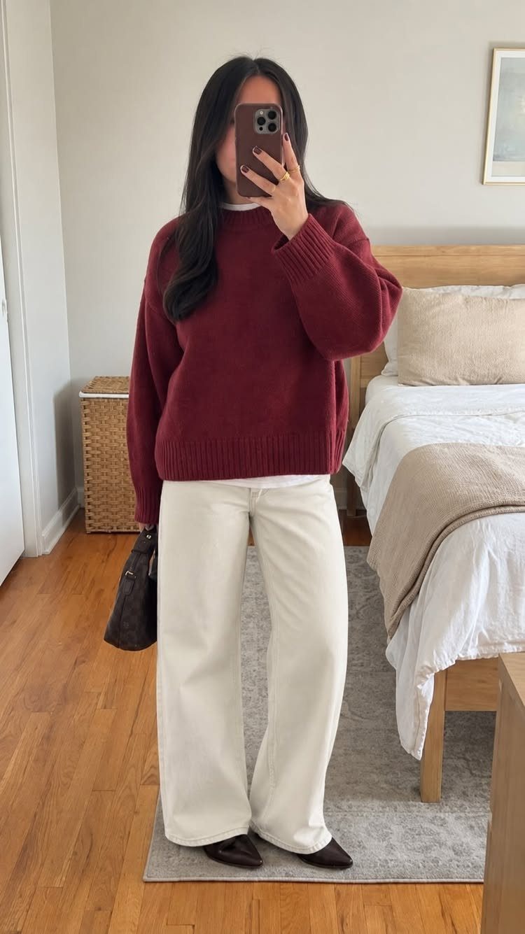 Woman in burgundy sweater and cream wide-leg pants posing for a mirror selfie.