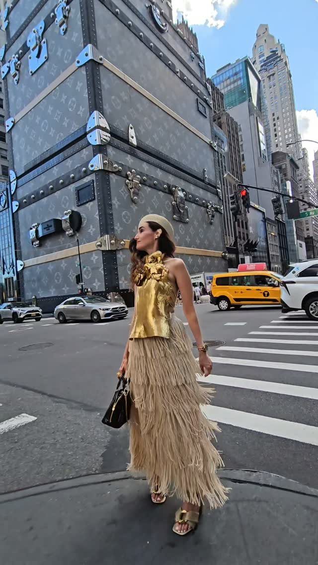 Woman wearing a metallic gold top and tiered fringe skirt on city street