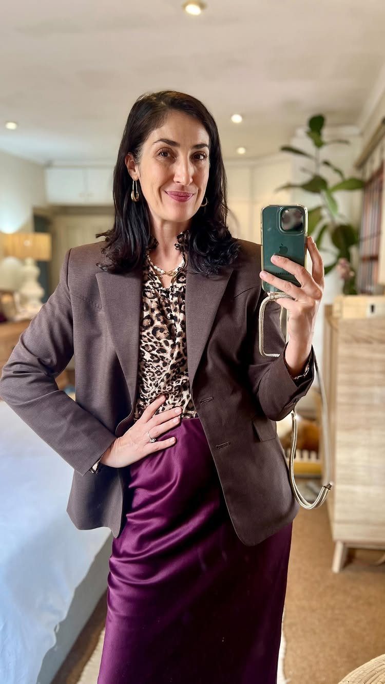 Woman wearing a brown blazer, leopard print top, and purple satin slip skirt.
