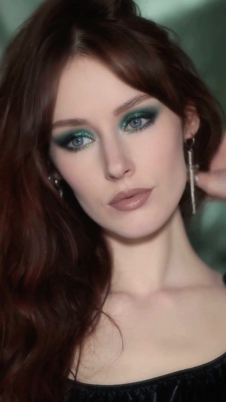 Woman with auburn hair wearing bold shimmering green eyeshadow and neutral lipstick.