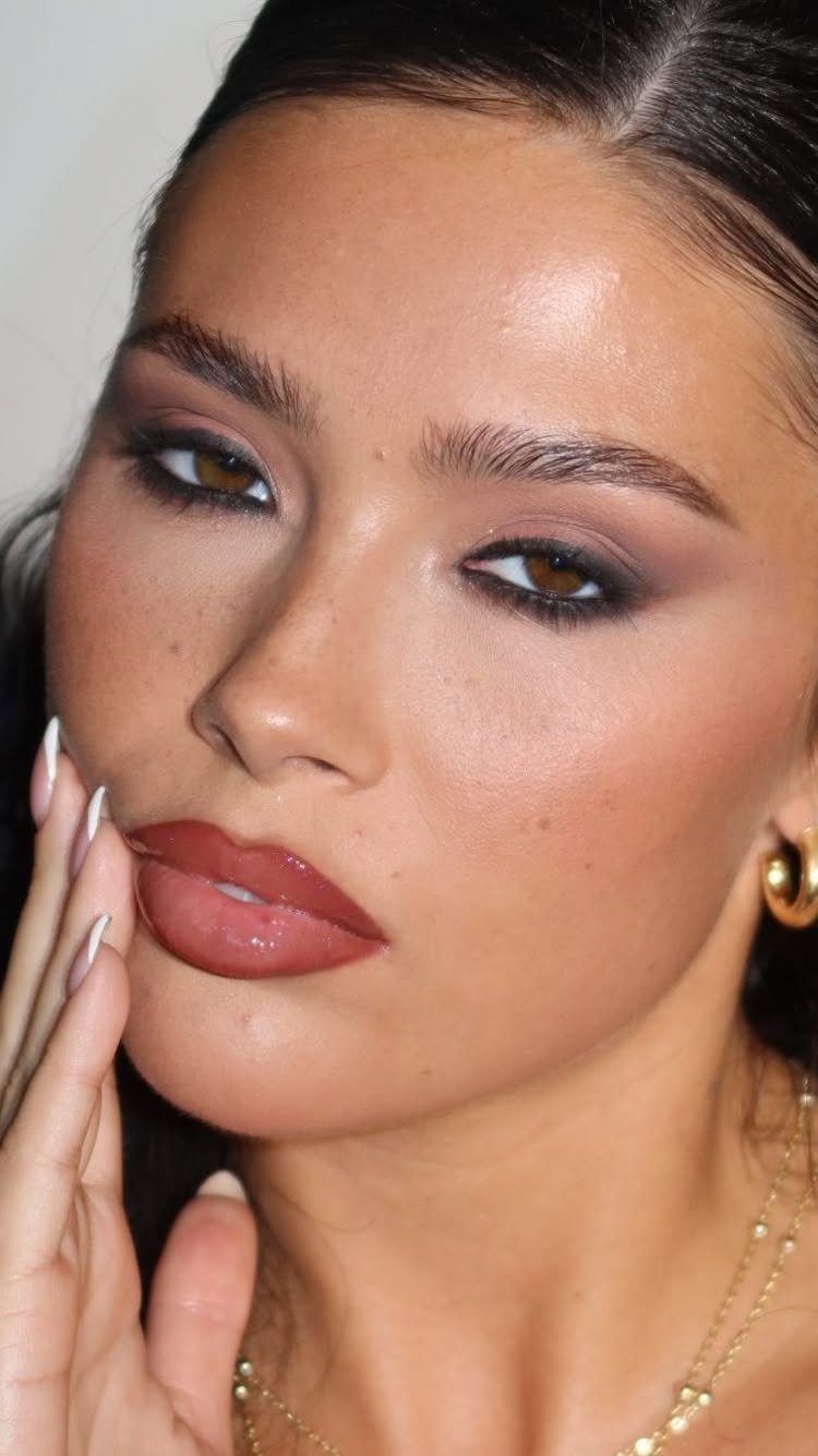 Woman with mauve eyeshadow and reddish-brown lips posing for a beauty portrait.