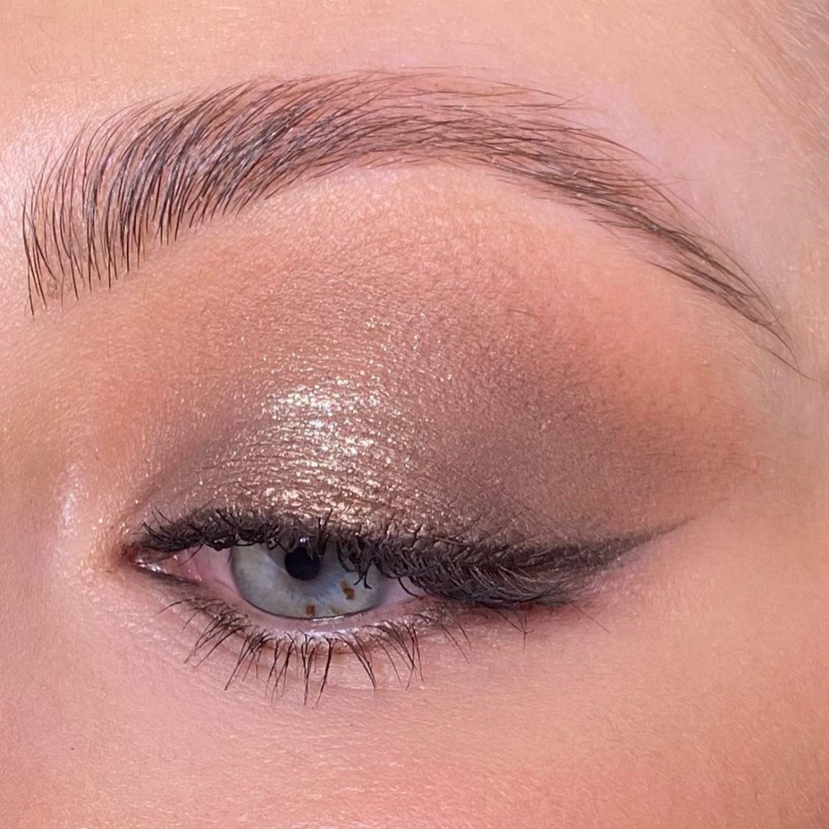Eye with metallic gold and bronze smokey eyeshadow and black winged eyeliner.