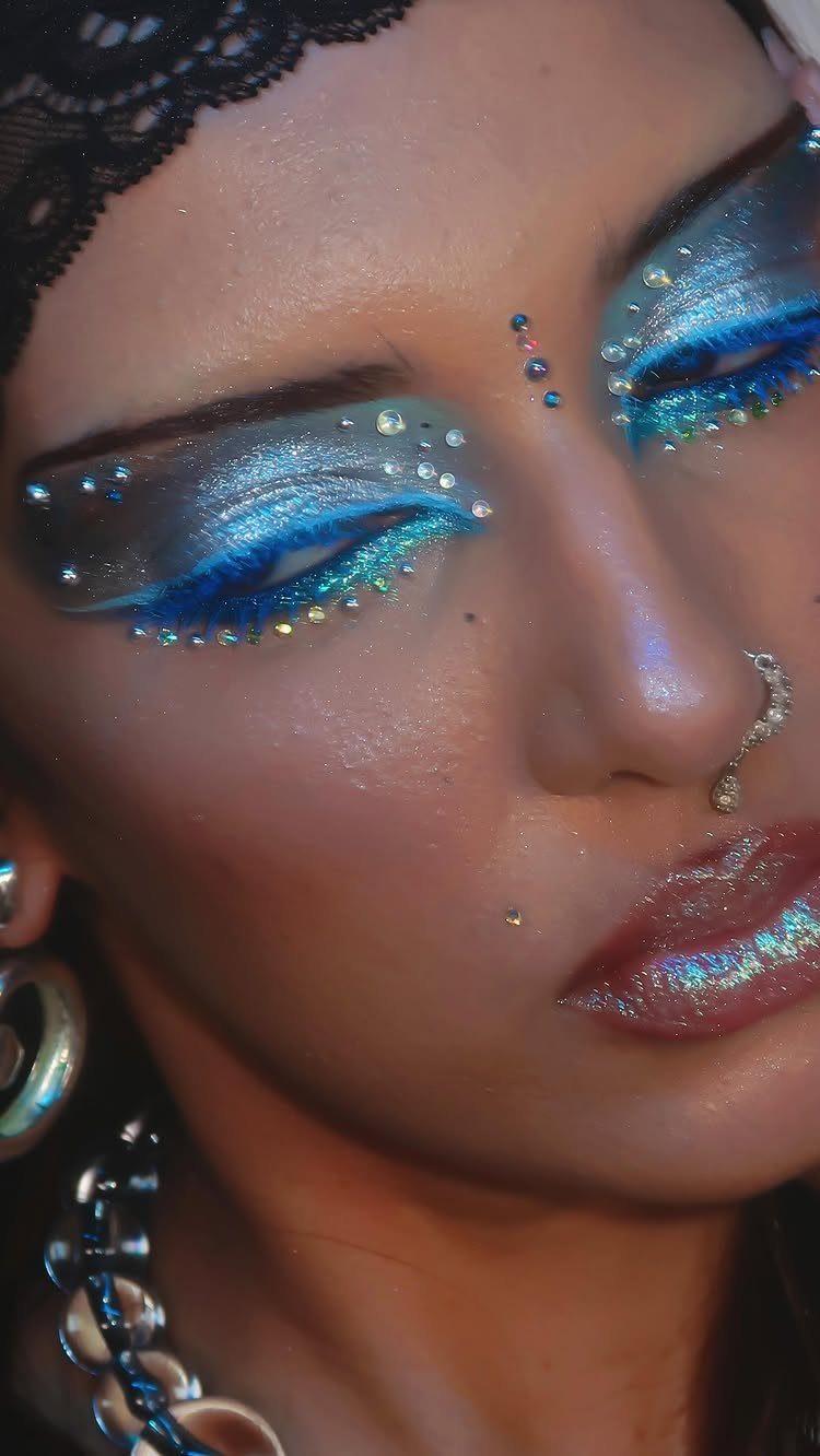 Person with shimmering blue eye makeup and rhinestones for a festive celebration.