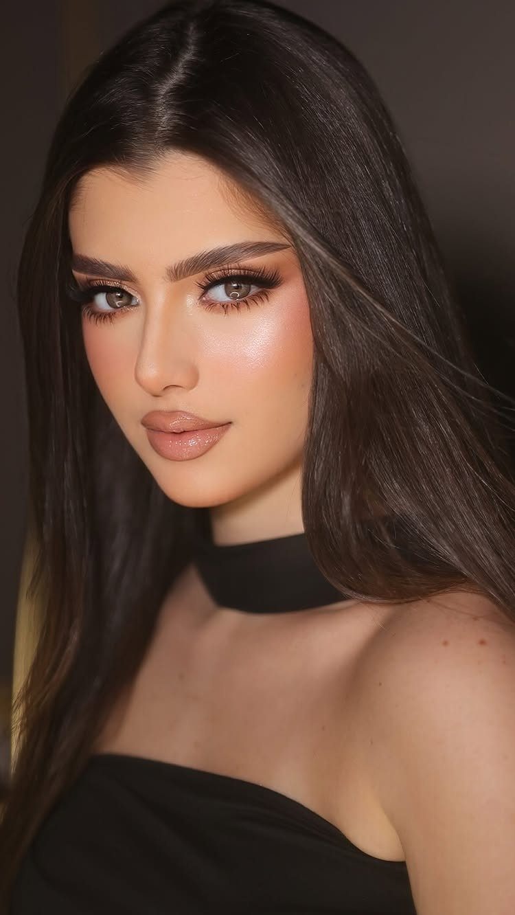 Woman with warm-toned shimmering eyeshadow, highlighted cheeks, and long dark hair.