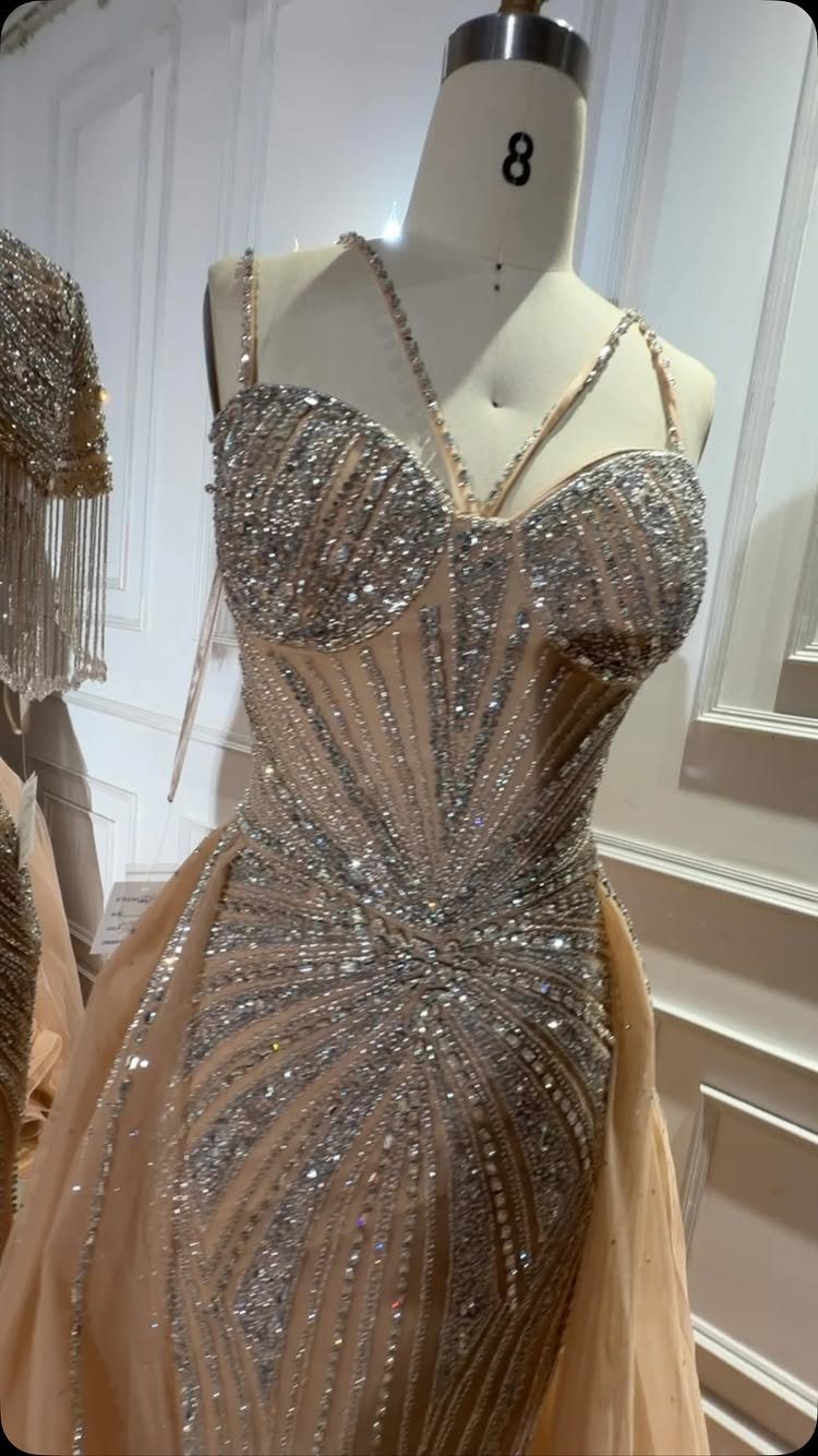 Champagne gown with silver sequin sunburst patterns displayed on a white mannequin.