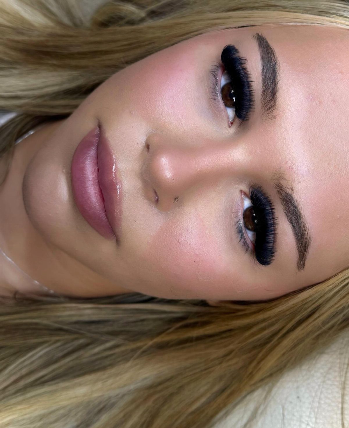 Woman with dramatic long eyelashes and glossy mauve lips in a close-up portrait
