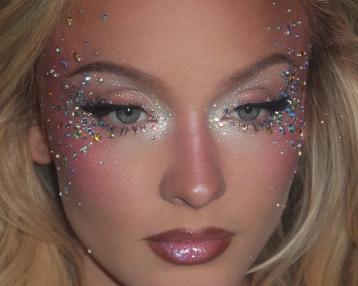 Woman with soft pink smoky eye makeup, matching cheeks, and iridescent gem accents.