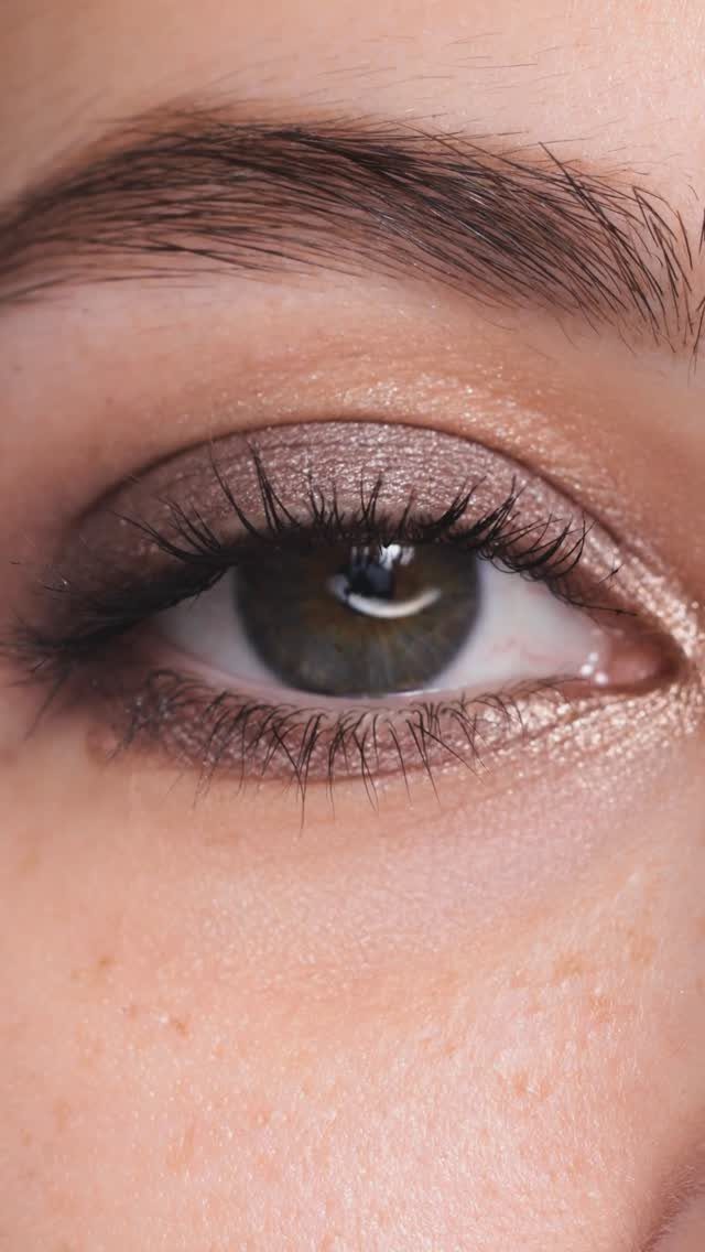 Close-up of an eye with shimmering bronze eyeshadow and dark mascara.