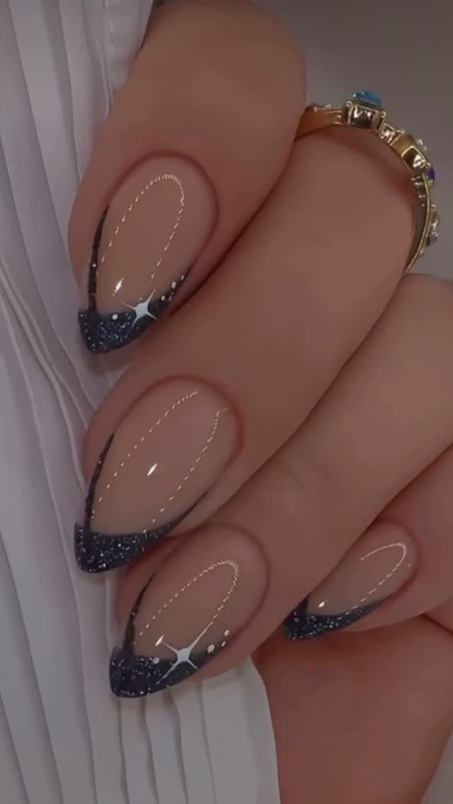 Almond nails with nude base, dark blue glitter tips, and white star accents.