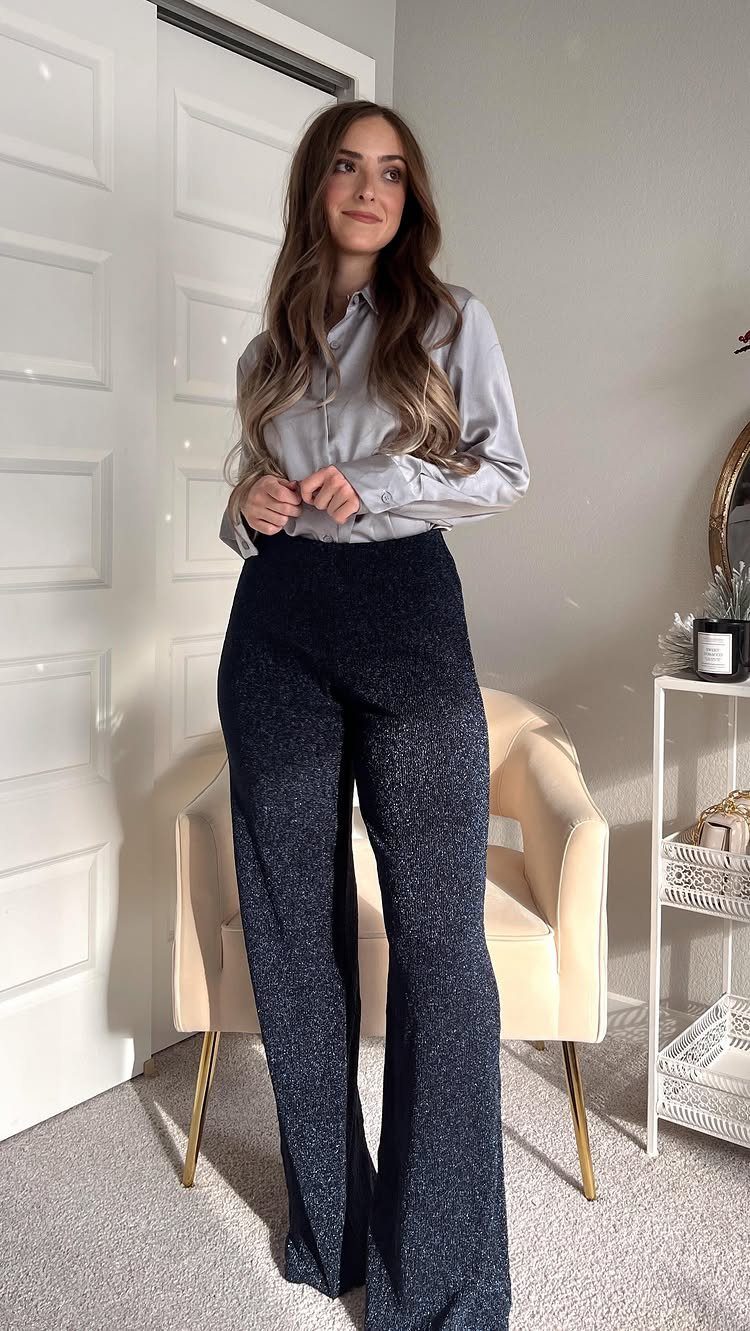 Woman wearing a silver satin shirt and shimmering navy wide-leg pants indoors.