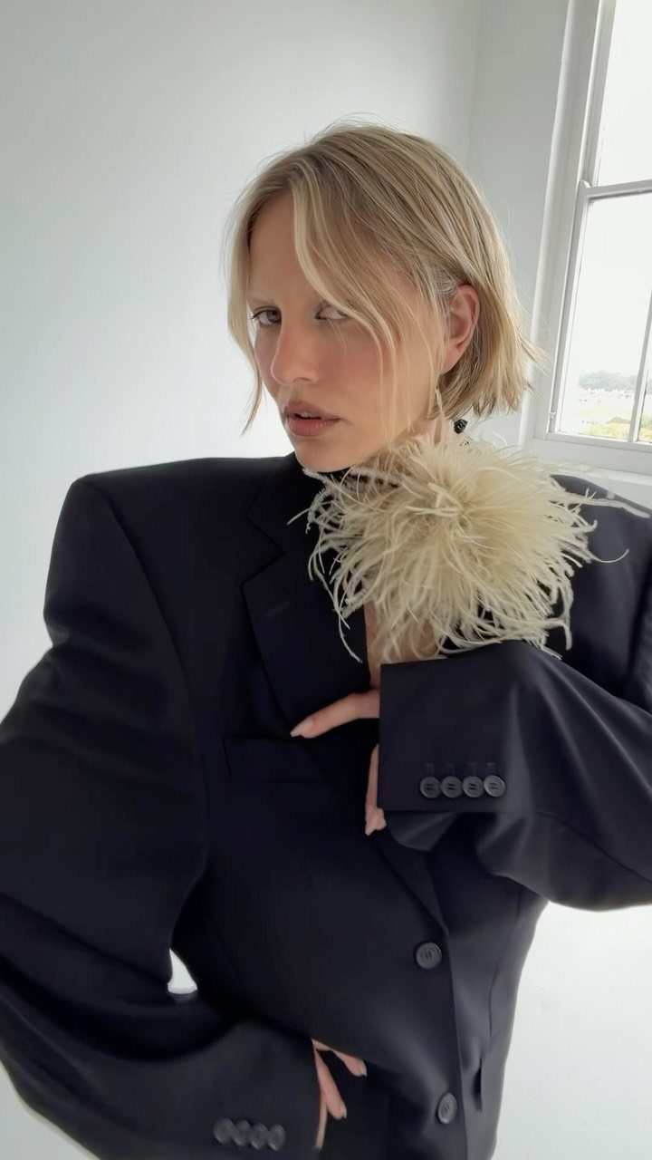 Woman wearing an oversized black blazer and a cream feather bandeau top.