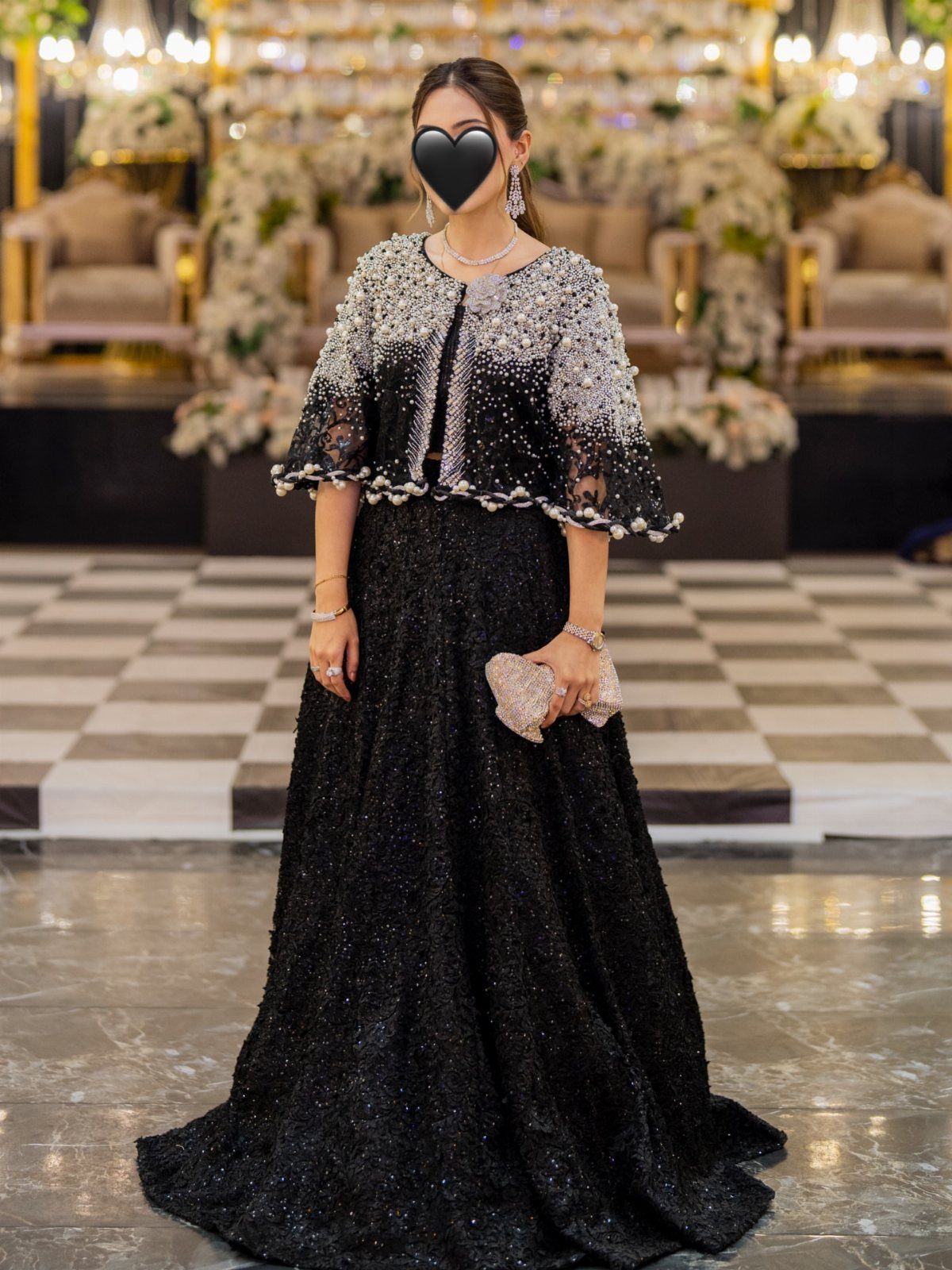 Woman in a floor-length black sparkling gown and embellished capelet in luxury setting